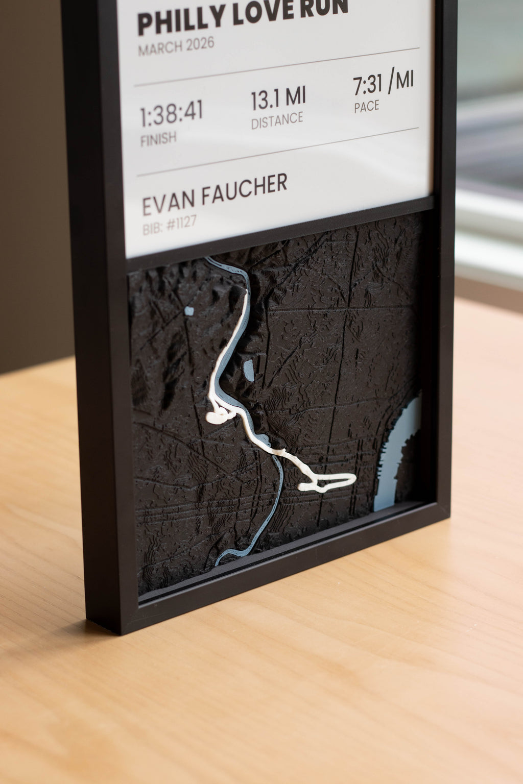 Close-up of a race panel stat sheet with finish time, distance and pace above a 3D printed course map